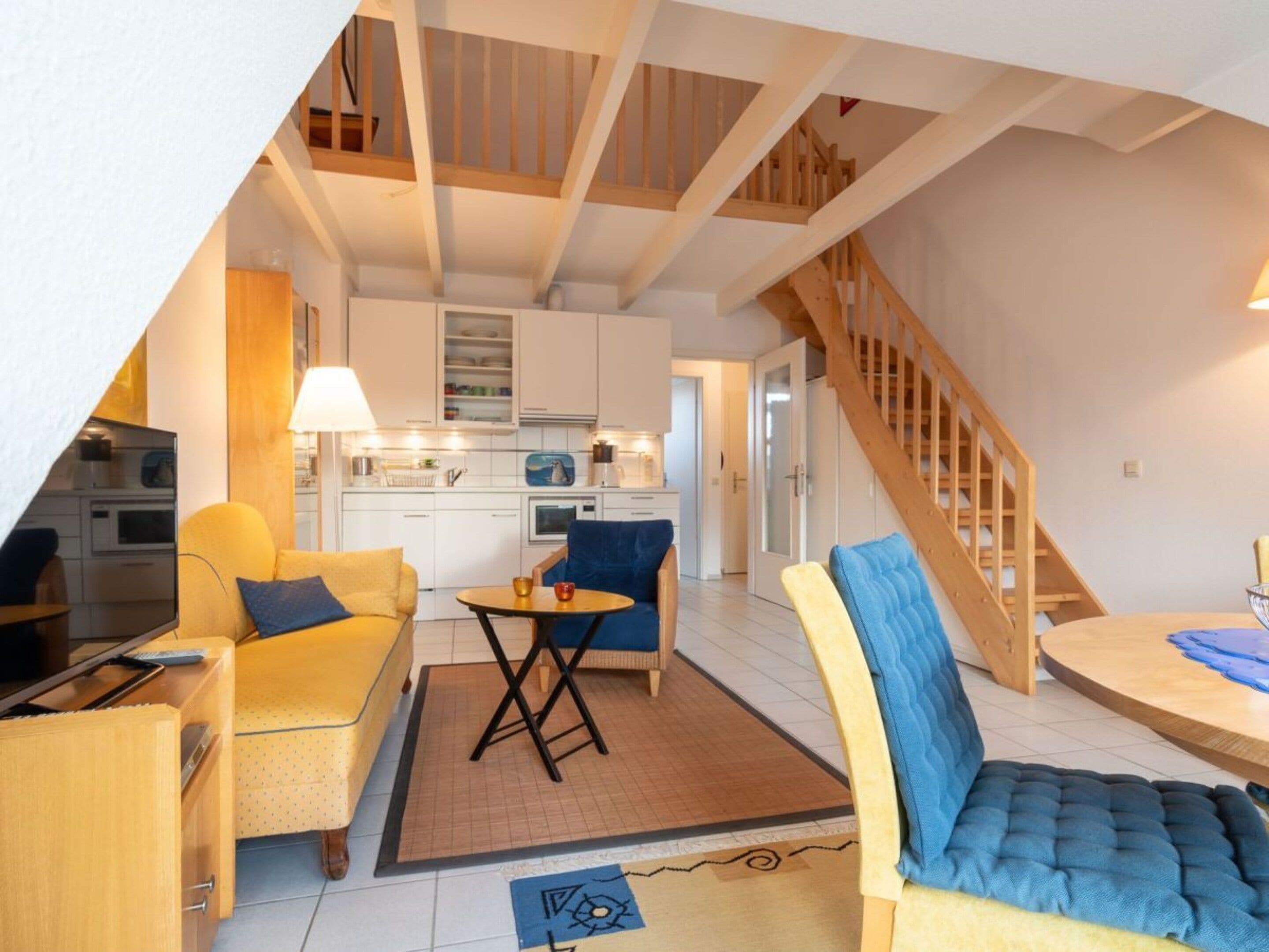 A compact living space with a kitchenette, a dining area, and a staircase.