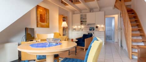 Um interior moderno com área de refeições, cozinha e escada de madeira.