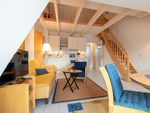 Eine moderne Wohnung mit Küche, Essbereich und Wohnzimmer, ausgestattet mit Holzbalken und einer Treppe.