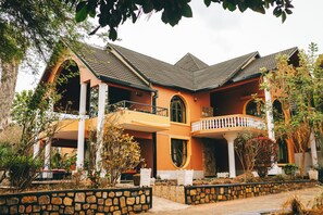 A two-story building with a balcony, stone walls, and a tiled roof.