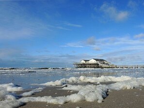 A coastal property with a pier extending into the sea, a sandy beach, and a clear sky. - House by the Lighthouse Apt. 02 (St. Peter-Ording)