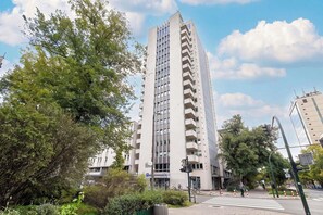 A high-rise building with multiple balconies, surrounded by greenery and a clear sky. - Cracow | aleja Kijowska 24 | Comfortable Apartment | Desk (Kraków)
