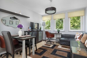 A modern living room with a dining area, a television, and a sofa. - Cracow | aleja Kijowska 24 | Comfortable Apartment | Desk (Kraków)