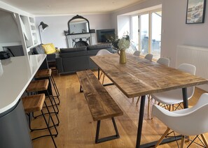 A modern living space with a dining area, kitchen, and seating.