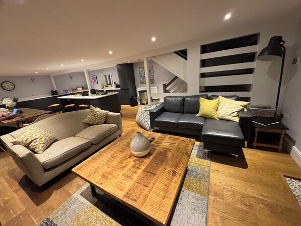 A modern living room with a sofa, coffee table, and a kitchen in the background.