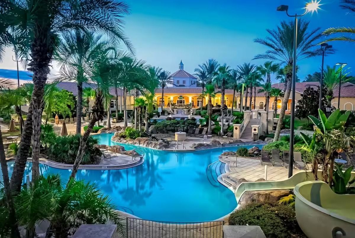 Un resort con piscina central, palmeras y un edificio con techo abovedado.