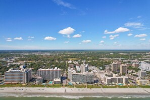 A coastal cityscape with high-rise hotels, a beach, and a clear sky. - Oceanfront Sand Dunes Condo w/ Pools (Myrtle Beach)