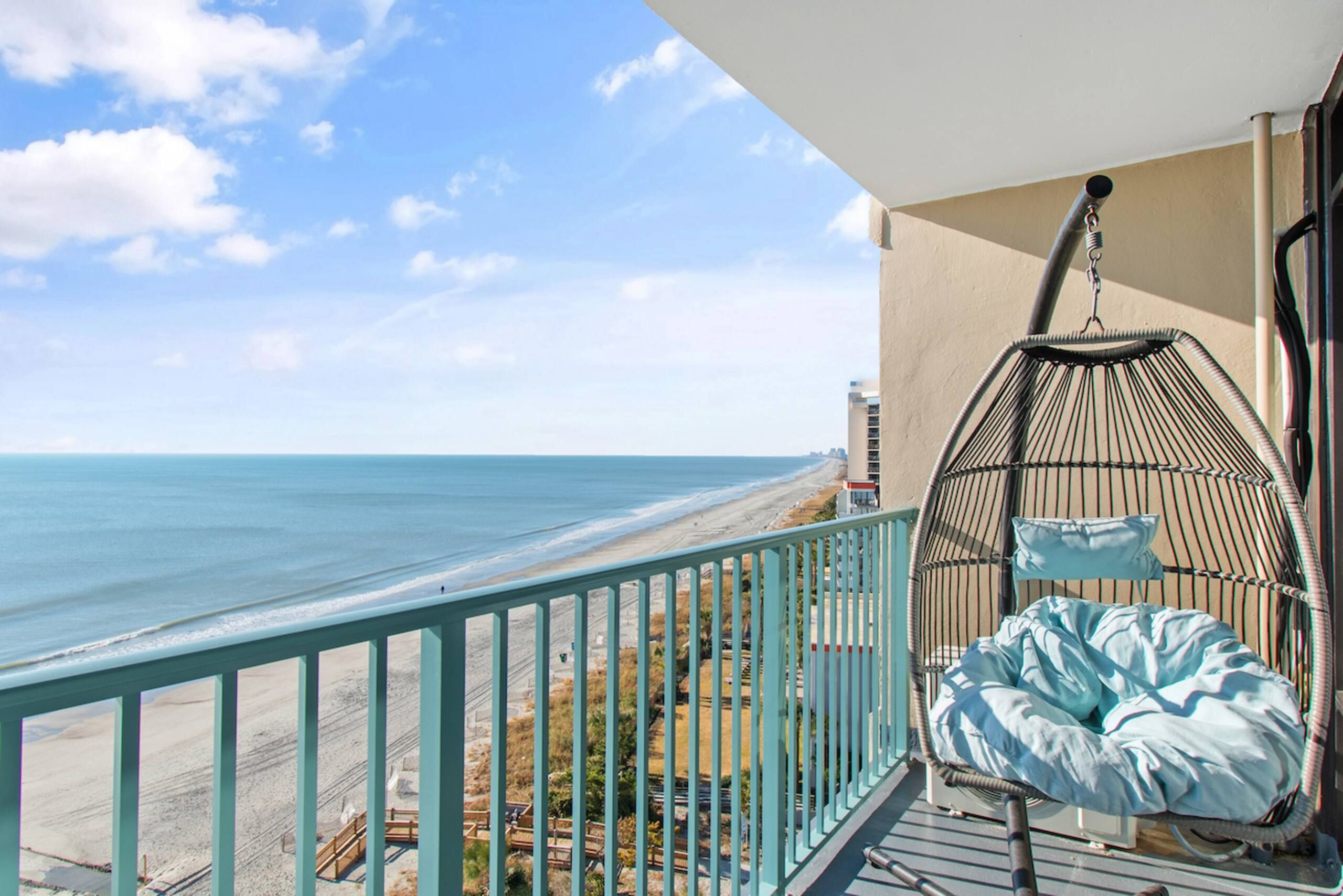 A balcony with a view of the beach and ocean.