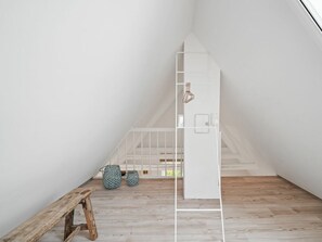 A minimalist room with a wooden bench, a white ladder, and a small staircase. - Sonnengold Apartment Sonnengold (St. Peter-Ording)