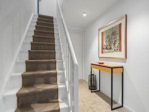 A staircase with carpeted steps and a white railing, leading to a room with a framed artwork on the wall. - Sonnengold Apartment Sonnengold (St. Peter-Ording)
