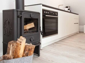 A modern kitchen with a black wood-burning stove and a built-in oven. - Sonnengold Apartment Sonnengold (St. Peter-Ording)