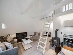 Ein modernes Loft mit Schlafgalerie, Kamin, Fernseher und Essbereich.