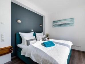 Ein Schlafzimmer mit einem Bett, einem Nachttisch, einer Wandleuchte und einem Gemälde.