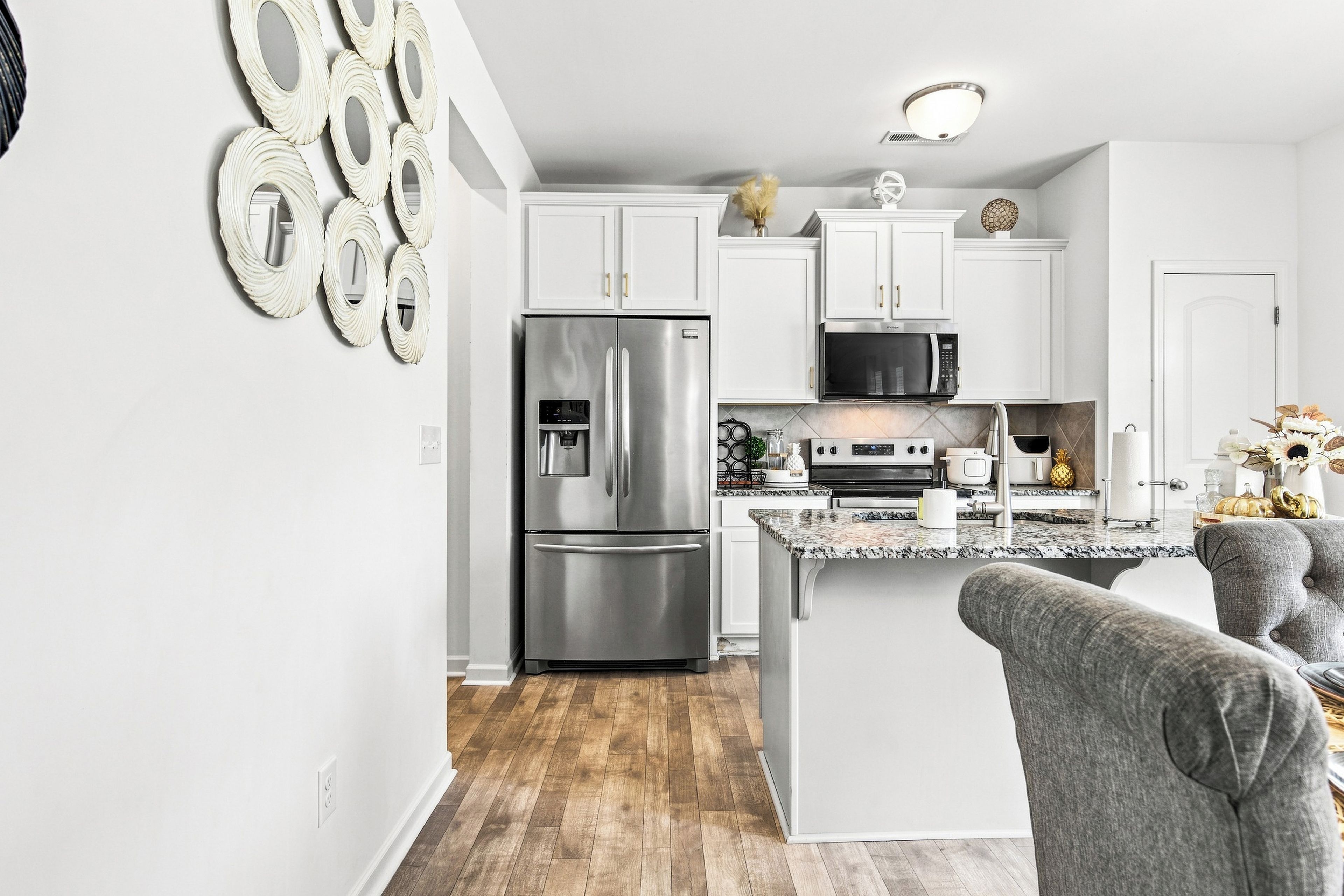 A modern kitchen with stainless steel appliances, white cabinetry, and a granite countertop.