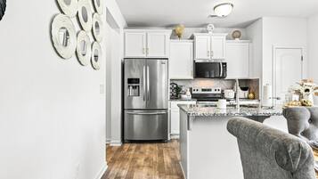 A modern kitchen with stainless steel appliances, white cabinetry, and a granite countertop.