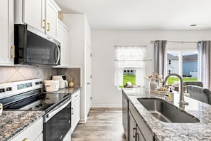 Una cocina moderna con microondas integrado, horno y una isla grande con pileta.