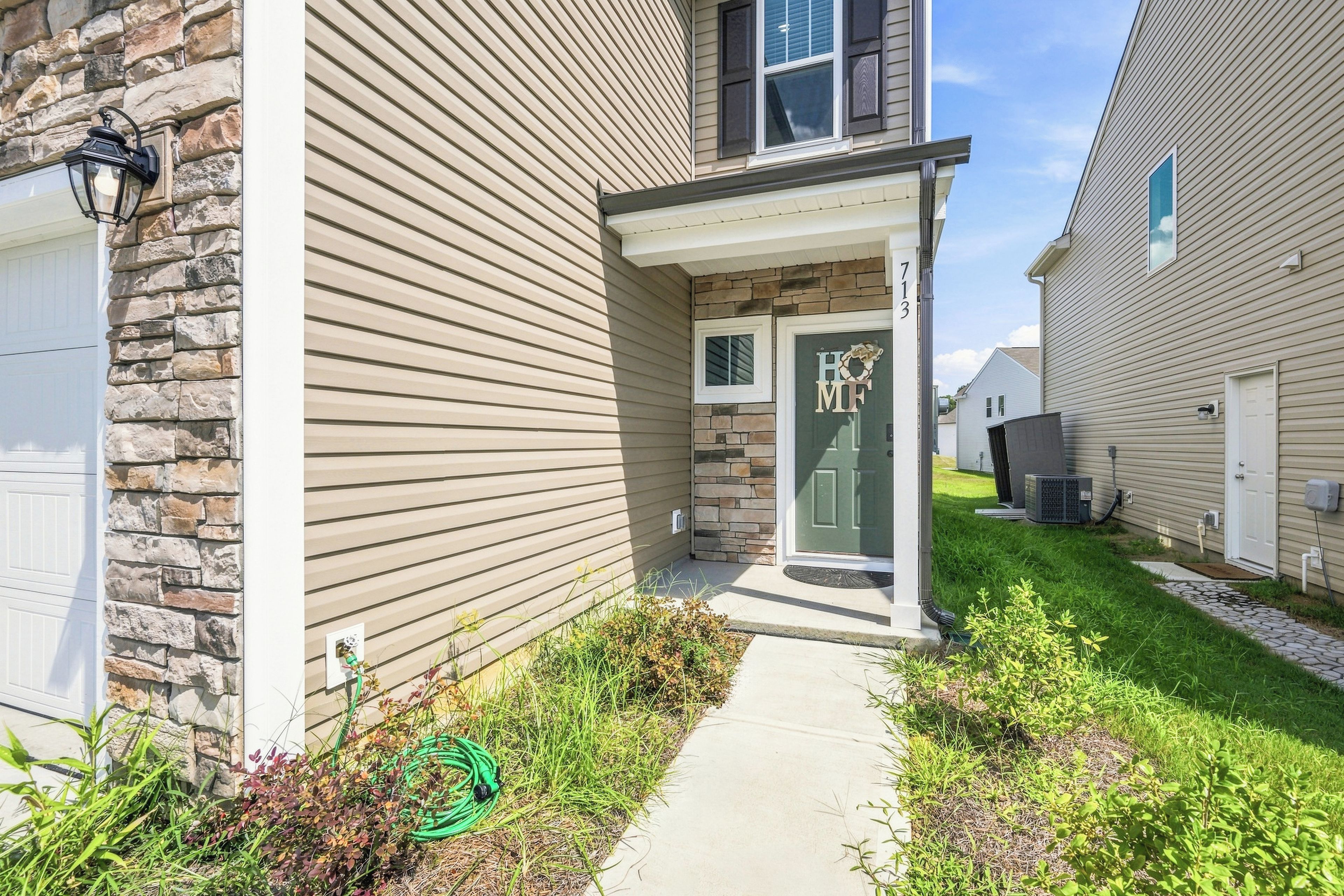 A residential house with a stone facade, a front porch, and a green door.