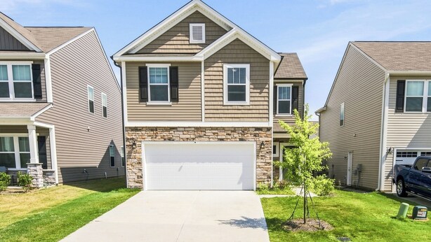 A two-story residential building with a stone facade, a garage, and a well-maintained lawn. - The Velvet Stay (Granite Quarry)