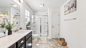 A modern bathroom with a double sink, a glass shower enclosure, and a white toilet. - The Velvet Stay (Granite Quarry)