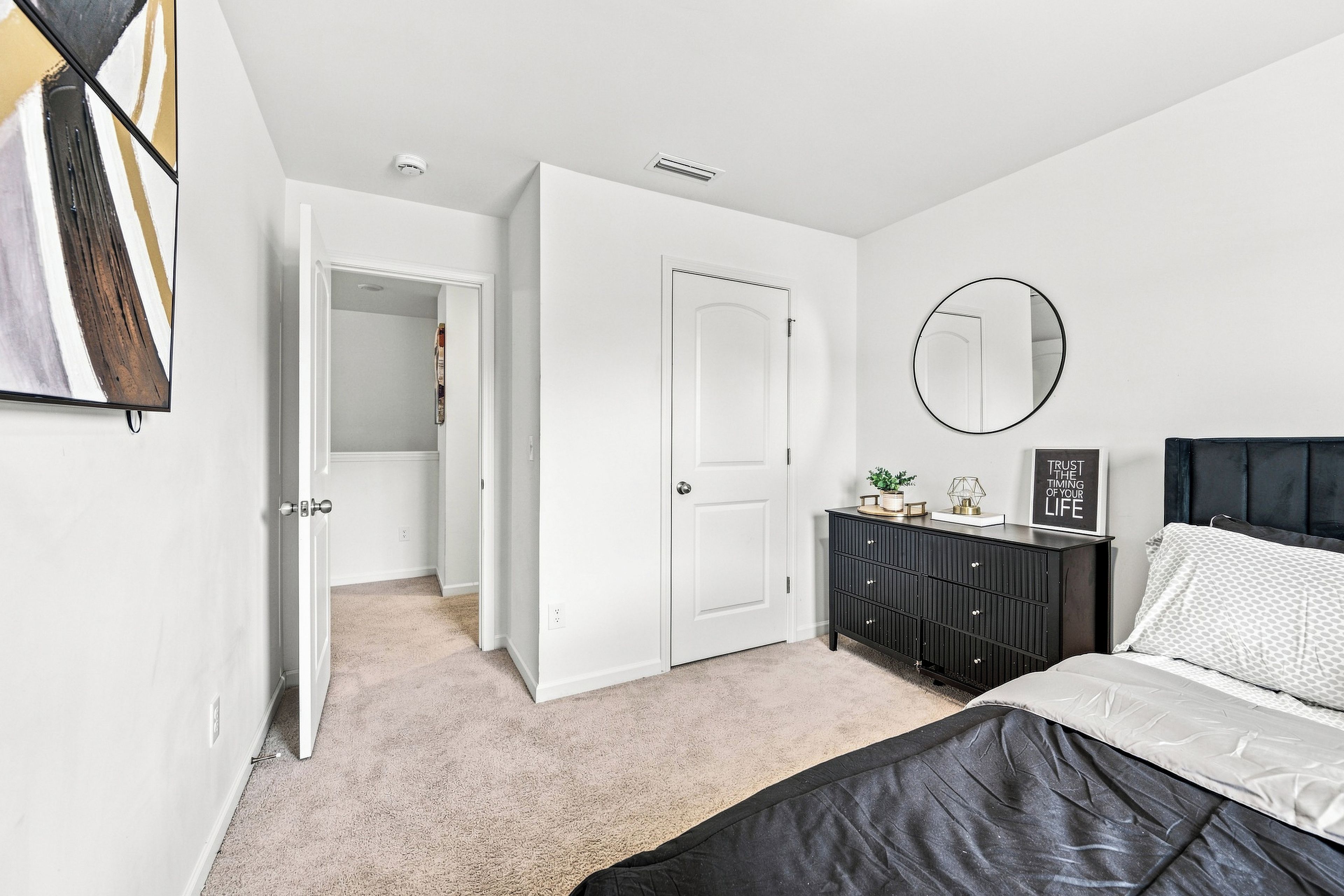 A bedroom with a bed, a dresser, a mirror, and a door leading to a closet.