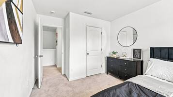 A bedroom with a bed, a dresser, a mirror, and a door leading to a closet.