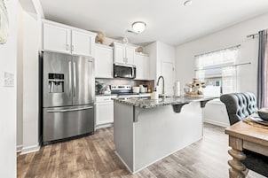 Una cocina moderna con electrodomésticos de acero inoxidable, encimera de mármol y comedor con mesa y sillas de madera.