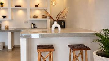 Una cocina moderna con una isla central, taburetes de madera e iluminación colgante.