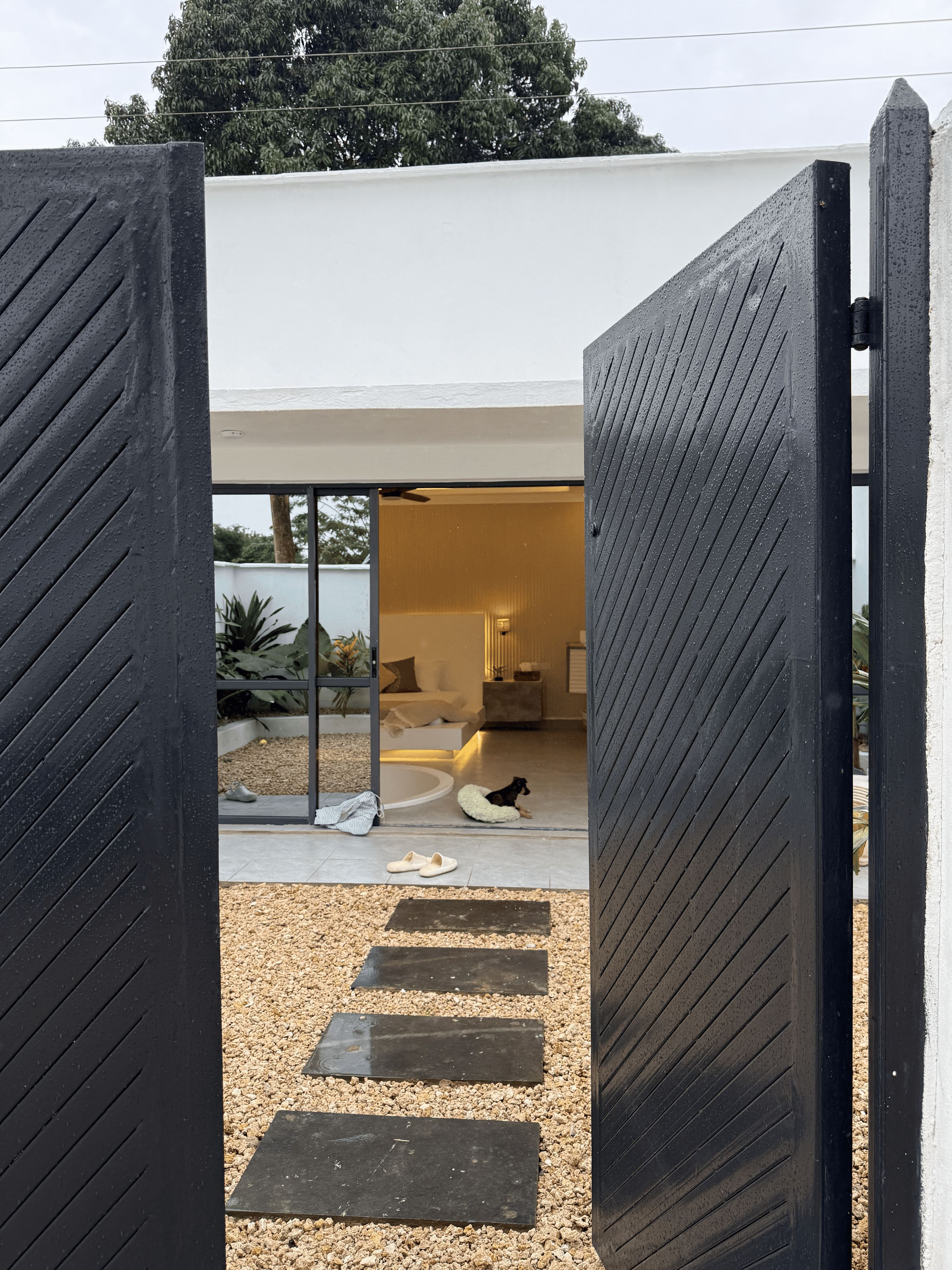 A modern house with a large open doorway leading to a living area with a dog bed and slippers on the floor.