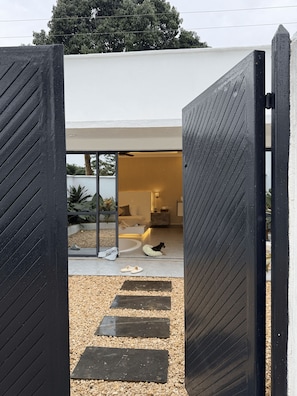 A modern house with a large open doorway leading to a living area with a dog bed and slippers on the floor.