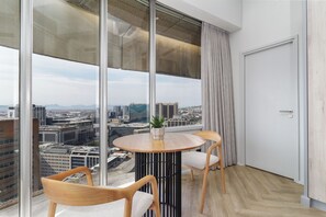 A modern room with a large window, a round table with two chairs, and a door. - Central CBD Apartment | Beautiful Views (Cape Town)