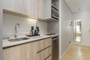 A modern kitchen with a built-in dishwasher, a coffee maker, and a kettle. - Central CBD Apartment | Beautiful Views (Cape Town)