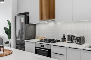 Eine moderne Küche mit einem Edelstahl-Kühlschrank, einem Einbauofen, einem Gasherd und einer Kaffeemaschine.