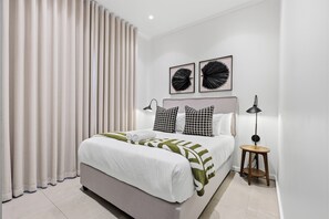 Ein modernes Schlafzimmer mit einem großen Bett, zwei Nachttischen und Kunstwerken an der Wand.
