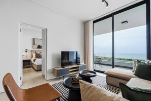 Moderni hotellihuone, jossa on parveke, televisio ja oleskelualue.