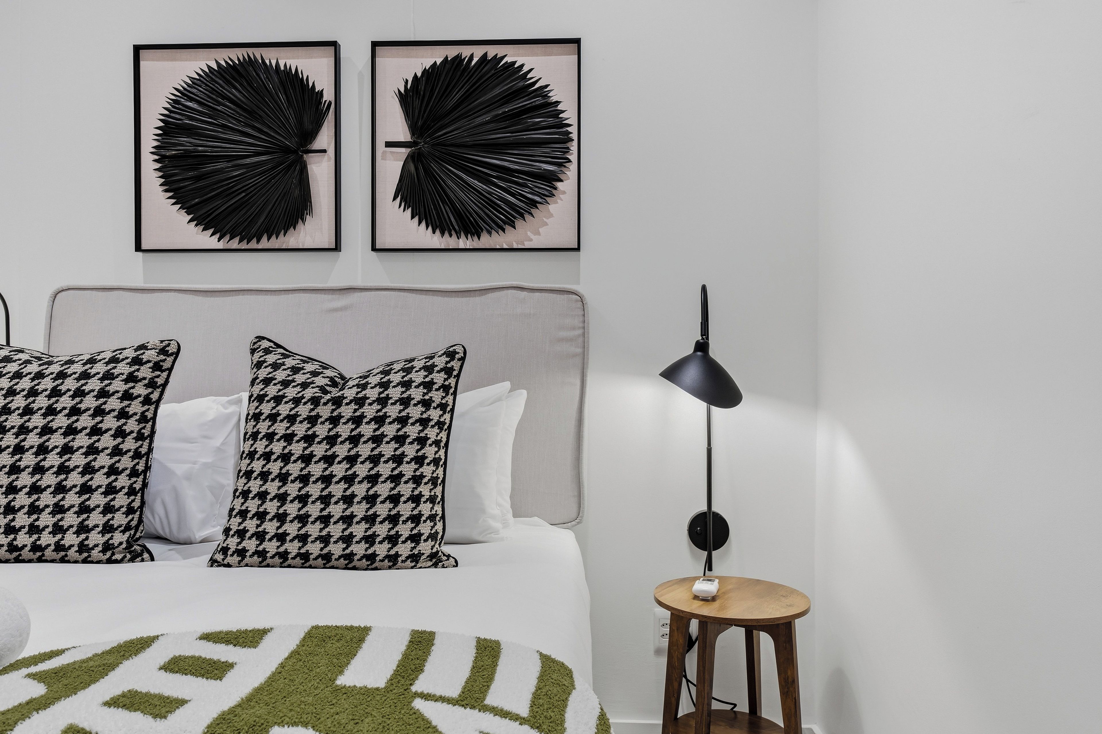 Une chambre à coucher comprenant un lit, deux œuvres d’art accrochées au mur, une lampe de chevet et une petite table en bois.