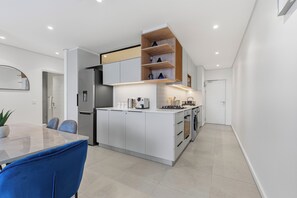 A modern kitchen with white cabinetry, a built-in oven, and a coffee machine. - Ocean-View 2BR at The York | Balcony (Umhlanga)
