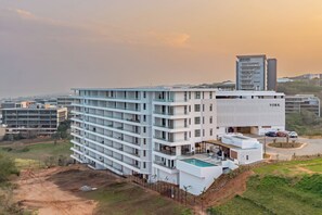 A multi-story hotel with a pool area and a parking lot. - Ocean-View 2BR at The York | Balcony (Umhlanga)