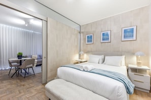 A modern hotel room with a large bed, a desk with a chair, and a view of the city through the window. - Refined City Living with a Contemporary Soul (Johannesburg)