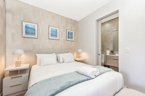 A modern bedroom with a bed, bedside tables, lamps, and a nightstand. - Refined City Living with a Contemporary Soul (Johannesburg)