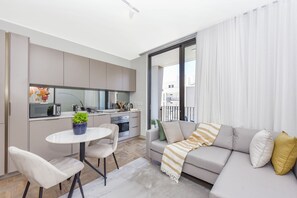 A modern apartment with a kitchenette, a dining area, and a living room with a sofa and a balcony. - Refined City Living with a Contemporary Soul (Johannesburg)