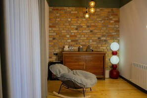 Ein Zimmer mit Backsteinwand, Holzschrank, Schaukelstuhl und Heizkörper.