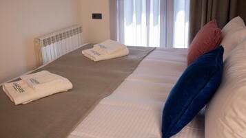 Habitación de hotel con cama, radiador y ventana con cortinas.