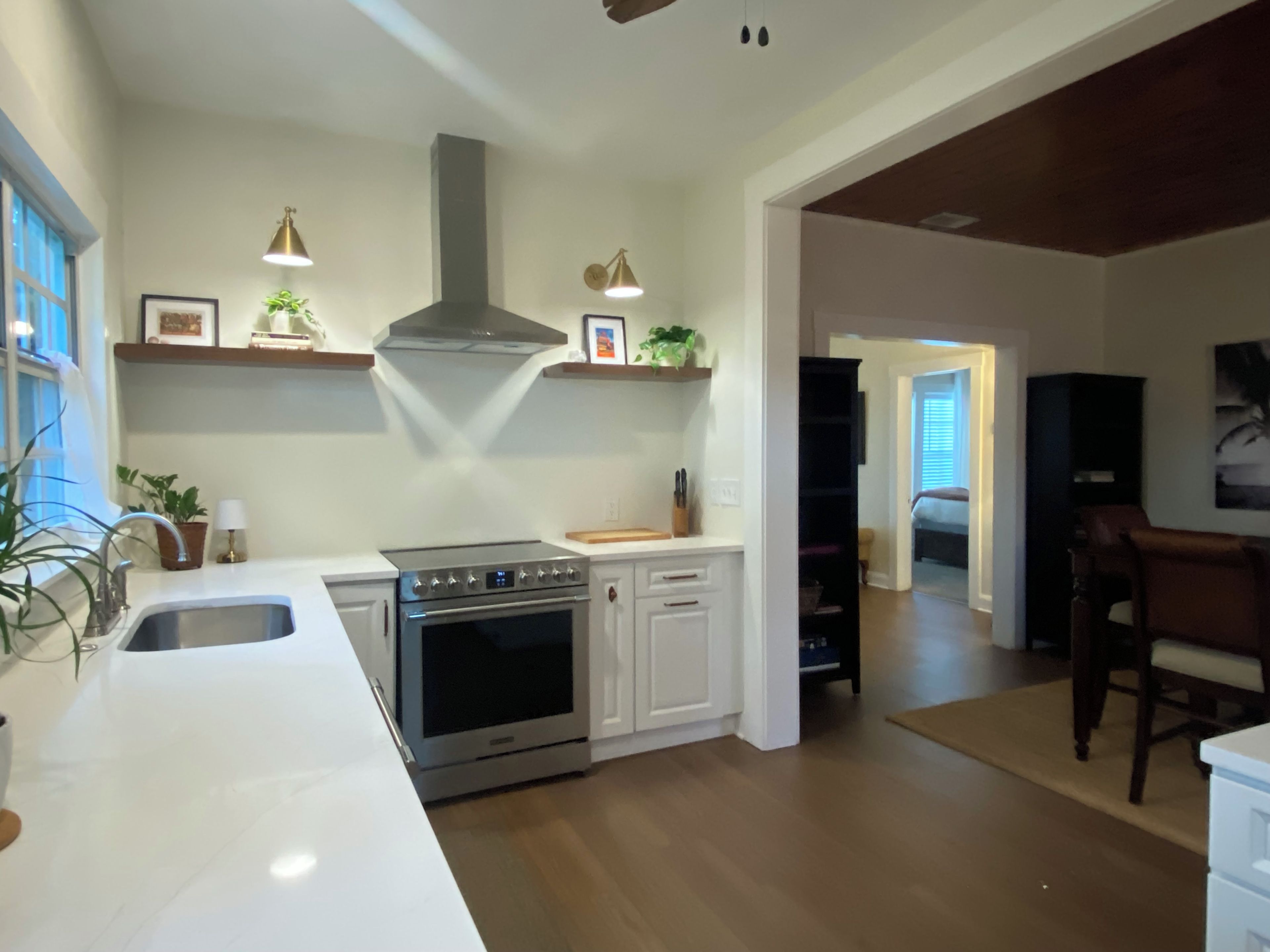 Una cocina moderna con armarios blancos, electrodomésticos de acero inoxidable e iluminación colgante.