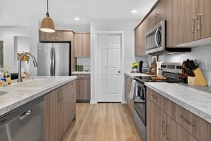 A modern kitchen with wooden cabinets, stainless steel appliances, and a marble countertop. - Golden Sage Gathering House | Pet-Friendly 4BR Nampa Home • Sleeps 10 • Gym • Fenced Yard (Nampa)