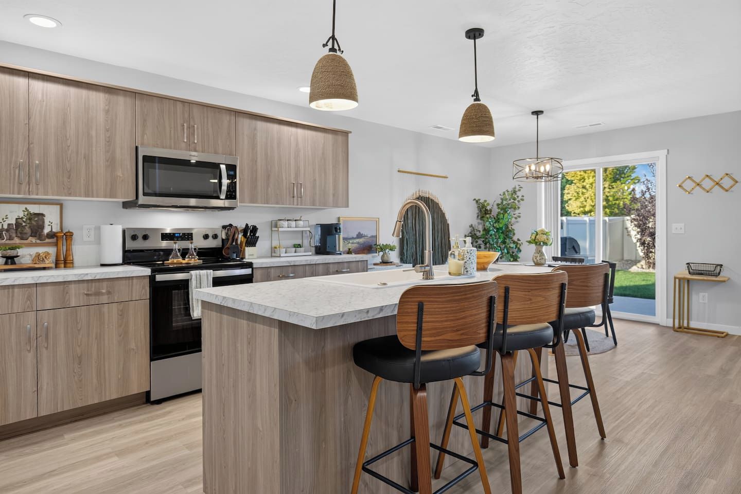 A modern kitchen with wooden cabinets, stainless steel appliances, and a central island with bar stools.