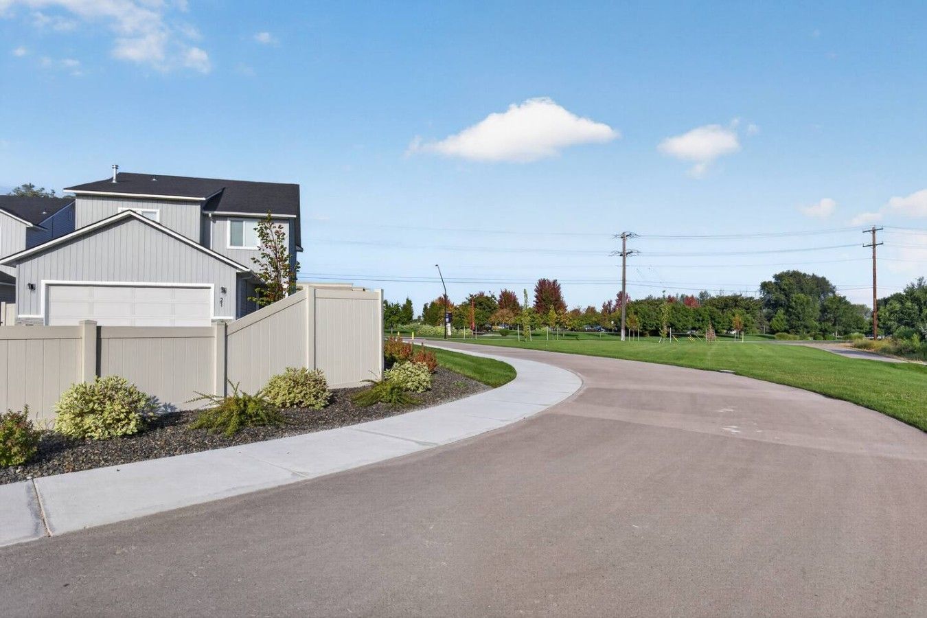 A residential street with houses, a curved driveway, and a grassy area with trees.