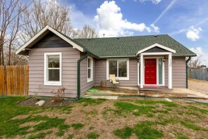 A single-story house with a red door, a covered porch, and a small front yard. - Morning Star Cottage (Star)