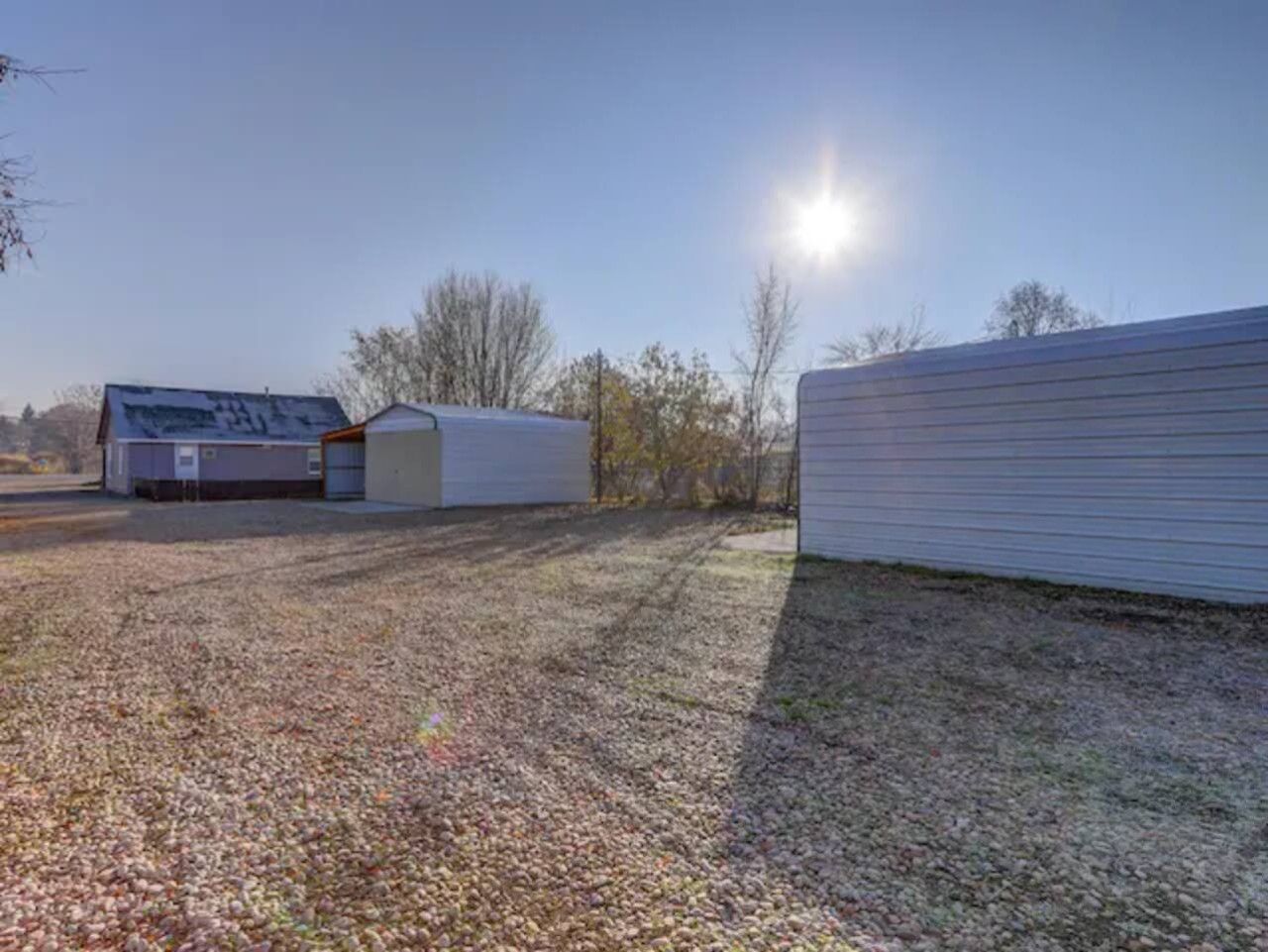 A residential property with a fenced yard, a detached garage, and a house with a sloped roof.