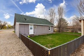 A single-story house with a fenced yard, a door, and a small porch. - Morning Star Cottage (Star)