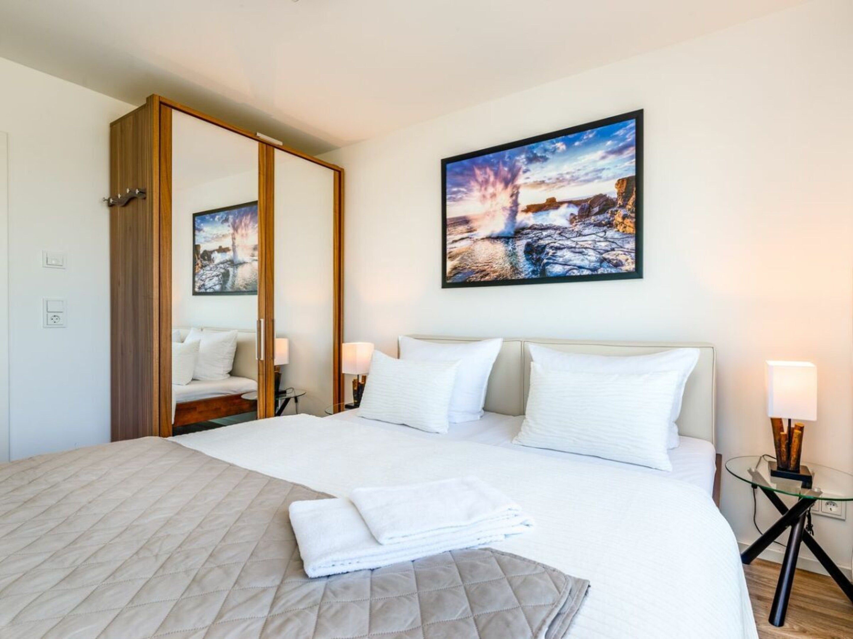 Une chambre d’hôtel avec un lit, une table de chevet, un miroir et un tableau au mur.